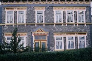 Hausfassade mit zahlreichen Schmuckelementen: Fensterbank, Fenstersturz, Kapitelle, Schmuckplatten, figürlicher Schmuck