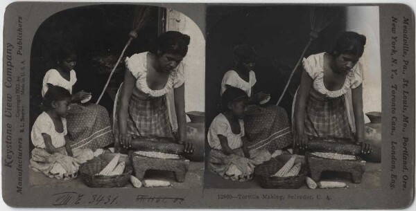 Femme indienne avec deux filles préparant une tortilla. La femme moud les grains de maïs.