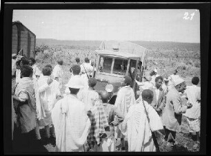 zwischen Dschibuti (Stadt) (Dschibuti) und Addis Abeba (Äthiopien): Lastkraftwagen, umringt von Einheimischen (Blick aus dem Waggonfenster)