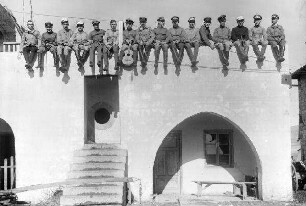 Unterhaltung bei Abteilung 304: Soldaten auf Hausmauer sitzend