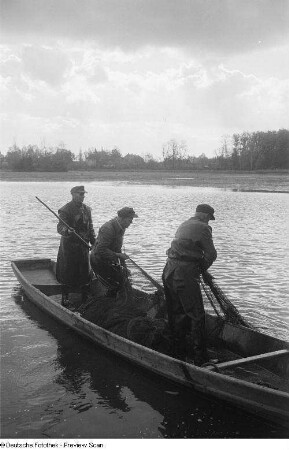 Fischer auf einem Boot beim Einholen des Netzes