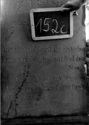 Grabstein 152 (Index: 100111310) Material: Sandstein Zustand: leicht verwittert Maße HxBxT: 170x60x30 cm Beschreibung: Stele, getreppter Sockel, giebelartiger Abschluß mit Verdachung, rechteckiges Schriftfeld eingetieft Symbolik: Kranz mit Schleife: Grabstein 152C