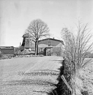 Wolkenweher Dorfstraße: Rumpf einer Windmühle, rechts davor ein Gebäude