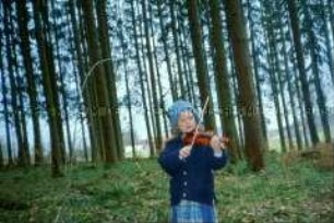 Geige spielende Schwester vor einem Waldstück (Altersgruppe bis 14)