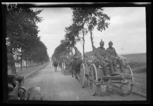 "An der Straße Cambrai (Dep. Nord, Frankreich) - Bapaume (Dep. Pas-de-Calais, Frankreich)": Fuhrwerkkolonne auf einer Allee (Rückansicht)