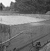Freibad: Reparaturarbeiten: neue Betonwand des Beckens: vorn rechts Arbeiter: im Hintergrund Bäume