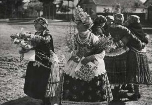 Ungarn. Volkstracht in Ungarn. Hochzeitskleidung. Im Hintergrund Tanzreigen