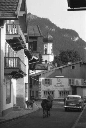 Oberammergau: Gasse mit Hund und Kuh, Hintergrund Kirche