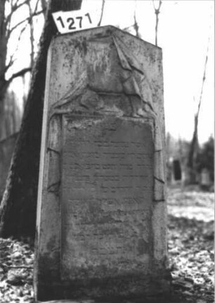 Grabstein 1271 (Index: 99900101) Material: Sandstein Zustand: stark verwittert Maße HxBxT: 133x55x21 cm Beschreibung: aufgesockelte Stele mit Dreiecksabschluss, eingetiefter Rahmen, im Dreiecksfeld plastiscje Urne, mit Tuch bedeckt Symbolik: Urne, mit Tuch bedeckt: Grabstein 1271 (Nachholaufnahme)