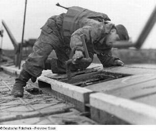 Deutschland . Nationale Volksarmee - Landstreitkräfte. Taktische Übung der Pioniertruppen. Pionier mit Steckschlüssel bei Montagearbeiten auf einem Ponton