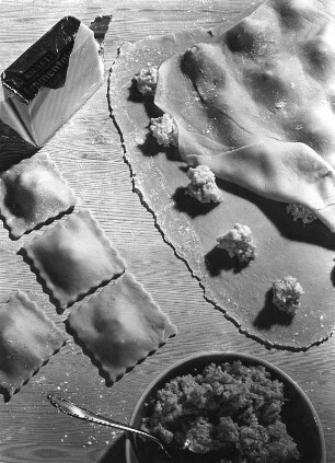 Krafts Rezeptaufnahmen. Gefüllte Nudelteigtaschen und ausgerollter Teig sowie Schale mit Füllung zur Herstellung