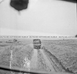 LKW der Wehrmacht auf einer Landstraße, aus einem LKW heraus fotografiert