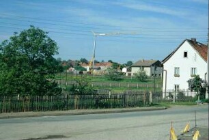 Blick über Gärten und Staketenzäune auf einen Baukran