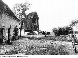 Mühlengehöft und Bockwindmühle, Sachsen (vor 1945). In der Einfahrt zweispänniges Rinderfuhrwerk mit Getreideladung