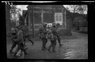 Metz-en-Couture (Dep. Pas-de-Calais, Frankreich): Soldaten mit Stahlhelm und Marschgepäck auf einer morastigen Ortsstraße