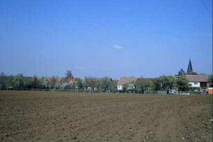 Blick über Acker zum Ort; Gärten und Dächer, Kirchturm