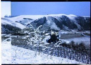 Breisach: Bildstock vor dem Brunnenturm [Vogtsburg: verschneiter Kaiserstuhl, Badberg, Altvogtsburg, Vordergrund Reben, 21.12.1976]