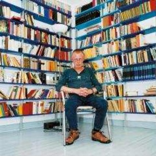 Sitzender Mann vor Bücherregalen (Altersgruppe 18-21)