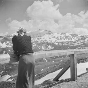 Frau mit Kopftuch blickt den Gipfeln der Alpen entgegen