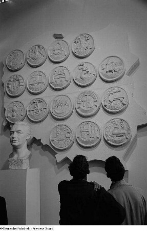 Zwei Besucher der Leipziger Herbstmesse 1954 betrachten Wappen von polnischen Städten