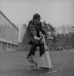 Frankfurt (Main)? Trimm Dich-Aktion. Mann auf einem Fahrradtrainer, wohl vor einer Schwimmhalle
