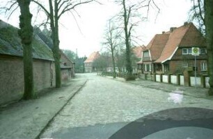 ehemaliges Gut Trenthorst-Wulmenau: Trenthorst: Straße mit Kopfsteinpflaster: im Hintergrund Bildmitte Kopfbau Wirtschaftshof [Karree]: vorne Bushaltestelle