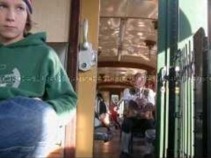 Blick in ein Eisenbahnabteil mit Fahrgästen, einer in bayrischer Lederhose (Altersgruppe 14-17)