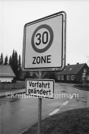 Redder: Verkehrsschild: hinten Wohngebäude und Bäume
