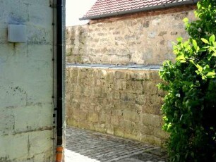 Kirchhofmauer im Südsüdwesten mit erhaltener Steinbrüstung des einstigen Wehrgangs (Schießscharten vermauert-hölzerne Teile abgetragen)