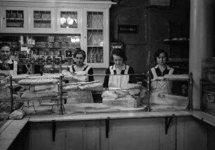 Dresden-Altstadt, Webergasse 35. Feinbäckerei und Conditorei Firma "Hermann Angermann", Inhaber Franz Seraph Schmid. Christstollenbäckerei. Ausstellen der Stollen im Geschäft. Vier junge Verkäuferinnen mit weißen Schürzen