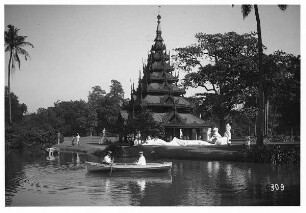 Rangun, schiefe Dagon Pagode : Rangun, Birma. Parklandschaft an einem Teich mit Touristen in Ruderboot, am Ufer Pagode mit großen Buddhastatuen