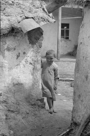 Zweiter Weltkrieg. Zur Einquartierung. Sowjetunion. Porträt eines kleinen Mädchens, hinter einer Mauer hervorlukend