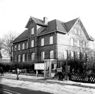 Schulstraße: Volksschule: davor Hecke: rechts Vorgarten und Jägerzaun: vorn Mitte Telefonzelle: links Schulkinder: Winter