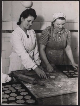 Die Leiterin der Küche mit dem Abzeichen des Deutschen Frauenhilfsdienstes und eine angehende Hausgehilfin beim Ausstechen von Plätzchen