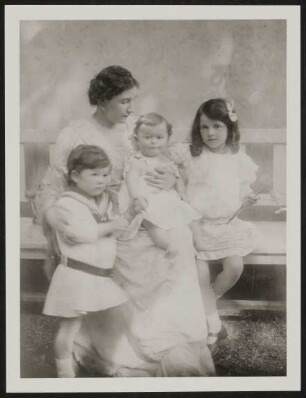 Gerty von Hofmannsthal mit ihren drei Kindern auf einer Holzbank sitzend