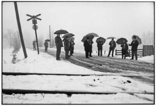 Maramures. Einheimische an einem Bahnübergang mit Regenschirmen