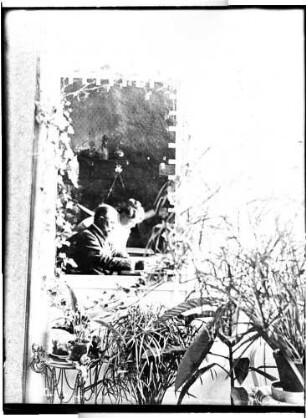 Wohnung der Familie Knochenhauer, Ehepaar Bruno und Fanny Knochenhauer am Tisch sitzend bzw. stehend. Blick (von der Veranda?) durch ein Fenster in das Zimmer : Kattowitz, Friedensstraße 2. Wohnung der Familie Knochenhauer, Ehepaar Bruno und Fanny Knochenhauer am Tisch sitzend bzw. stehend. Blick (von der Veranda?) durch ein Fenster in das Zimmer
