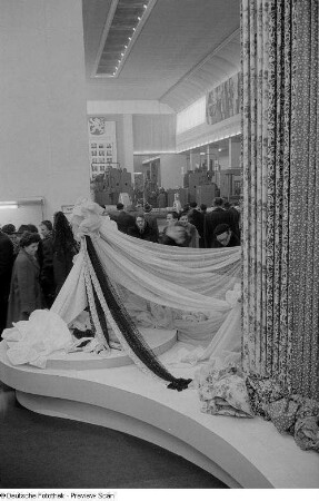 Besucher vor einem Messestand mit Stoffen auf der Ausstellungsfläche der Tschechoslowakei