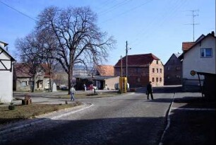 Dorfplatz mit Bushaltestelle, Telefonzelle, großem Baum, Konsum