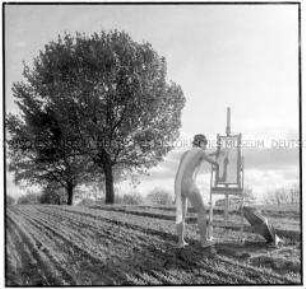Maler in freier Natur, mit einer Staffelei auf der ein Spiegel steht (Altersgruppe 18-21)