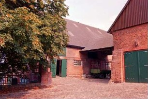 Fritz-Berodt-Straße 7-9: Hofanlage: westliches Wirtschaftsgebäude, Traufseite, mit Tor: Hofüberbauung zum östlichen Wirtschaftsgebäude, Giebelseite mit Lisene, Tor, darüber Fassadenplastik Pferdekopf, Giebel mit Verbretterung: davor Hofplatz mit Kopfsteinpflaster, Hofmauer mit Geländer: Baum: 19. August 1993