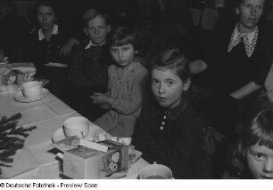 Kinder an einer gedeckten Tafel sitzend