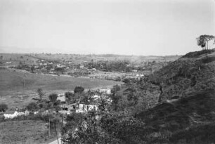 Landschaftsblick : Blick in ein Tal vom einem Park aus. An Fuße des Hügels verläuft eine Straße, an der Wohnhäuser stehen.