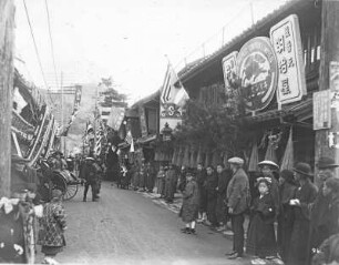 Nagasaki, Japan. Blick in eine belebte Geschäftsstraße mit Einheimischen und Touristen in Rikschas