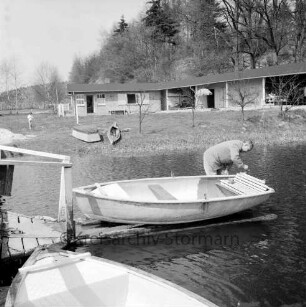 Badeanstalt: am Herrenteich: Frühjahrsputz: Bootsanleger am Badesteg: Bademeister Erwin Dombrowa bei Kontrolle der Ruderboote: hinten Liegewiese, Boote, junge Bäumchen: dahinter Bademeisterhaus, Bootshaus, Bäume