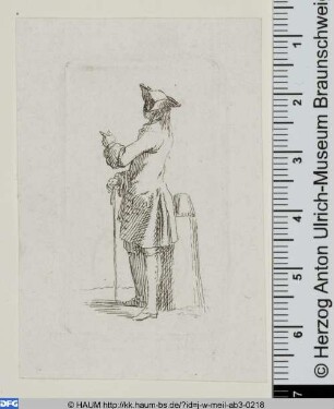 Rückenansicht eines jungen Mannes mit Hut und Stock neben einem einem Poller