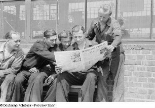 Arbeiter während des Lesens der Leipziger Volkszeitung
