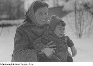 Eine Frau mit einem Kind im Arm in einer Schneelandschaft