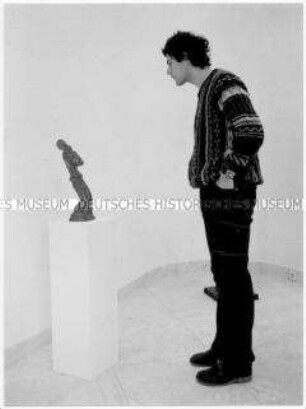 Junger Mann schaut sich eine Skulptur an (Altersgruppe 18-21)