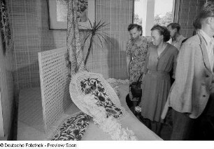 Besucher der Leipziger Herbstmesse 1954 beim Betrachten von Teppichen der indischen Sektion